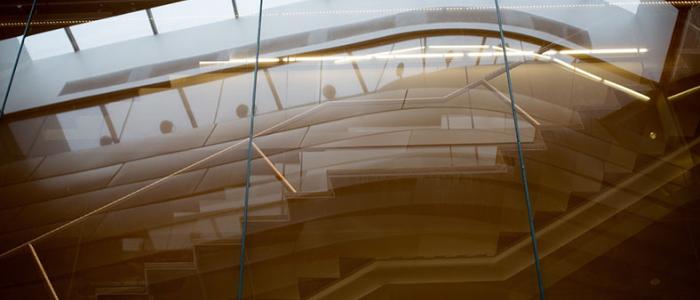 Architectural interior view of a modern staircase through reflective glass.