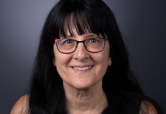 color portrait of woman with long dark hair and glasses