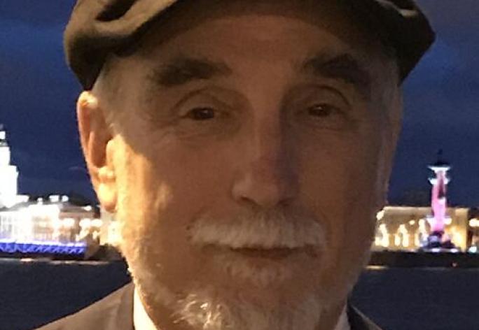 Man in suit and cap with beard looking at camera